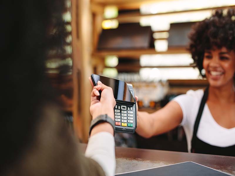 Store owner accepting contactless payments from phone.