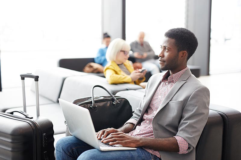 Man sitting at airport working on laptop. 