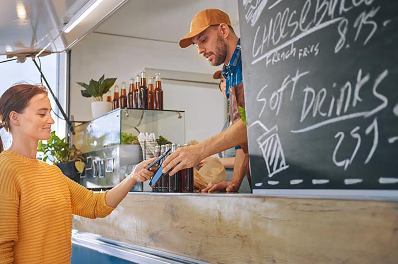 Soda business in a food truck accepting contactless payment from phone.