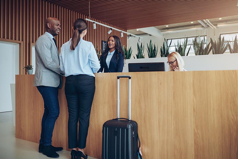 Couple at travel desk with two representatives behind the desk. 