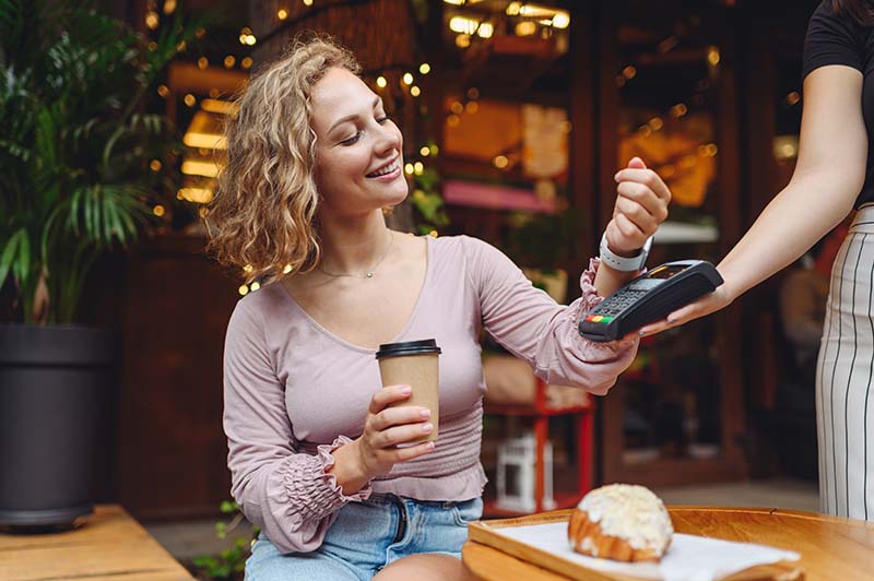 A person at a cafe using smartwatch to pay with digital wallet. 