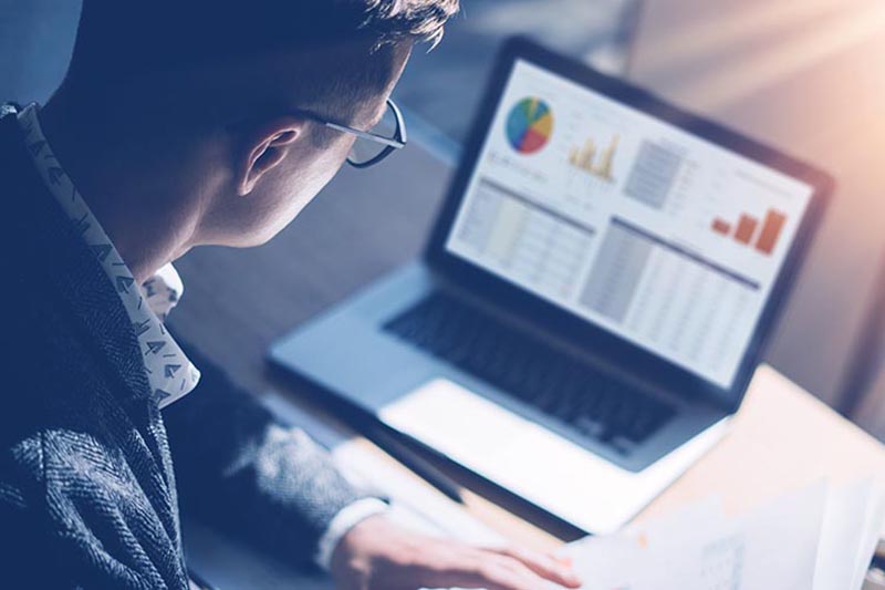 Businessman looking at financial report on laptop.