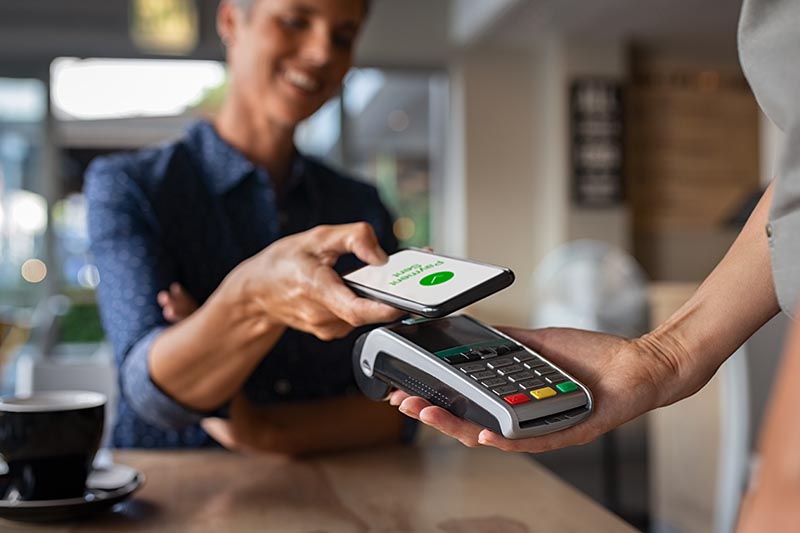 Someone using digital wallet on phone to pay for coffee. 