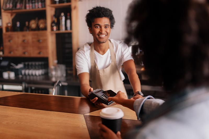 Cafe employee accepting contactless payment from phone. 