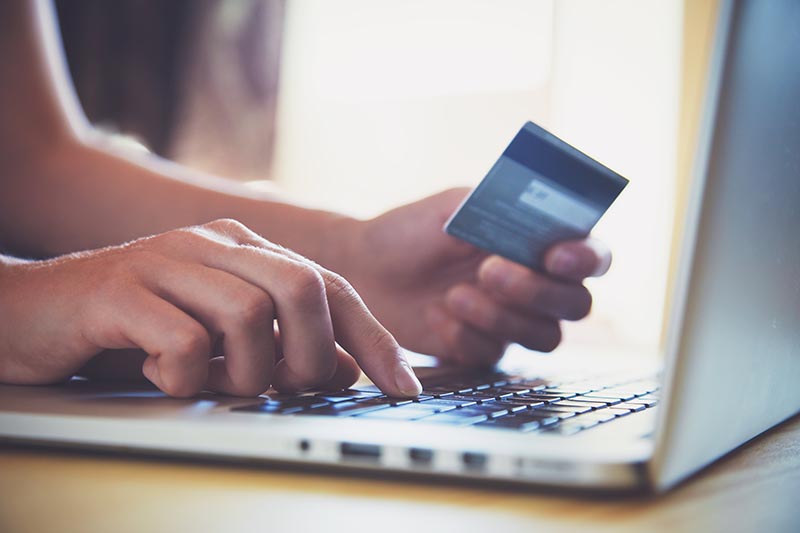 A person using laptop to pay online with credit card.