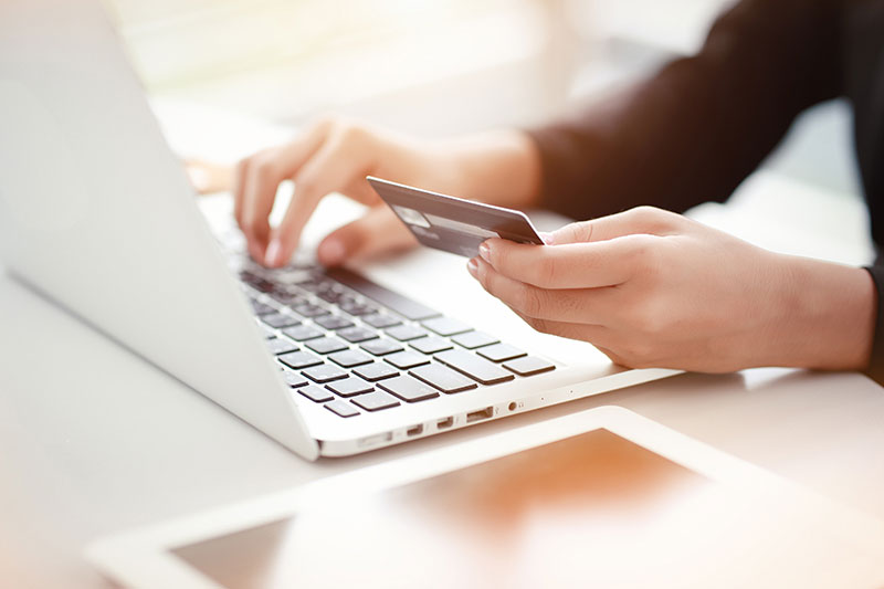 A person using credit card to pay online with laptop.