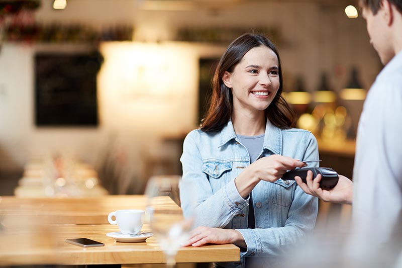 Woman at cafe paying on wireless payment gateway.