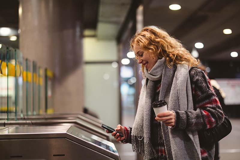 Woman paying for subway fare with digital wallet on phone. 