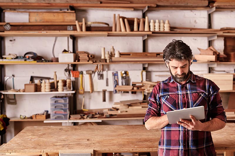 Business owner standing in front of woodworking shop. 