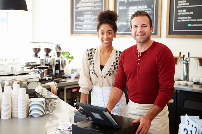 Small business owners running the cash register at cafe. 