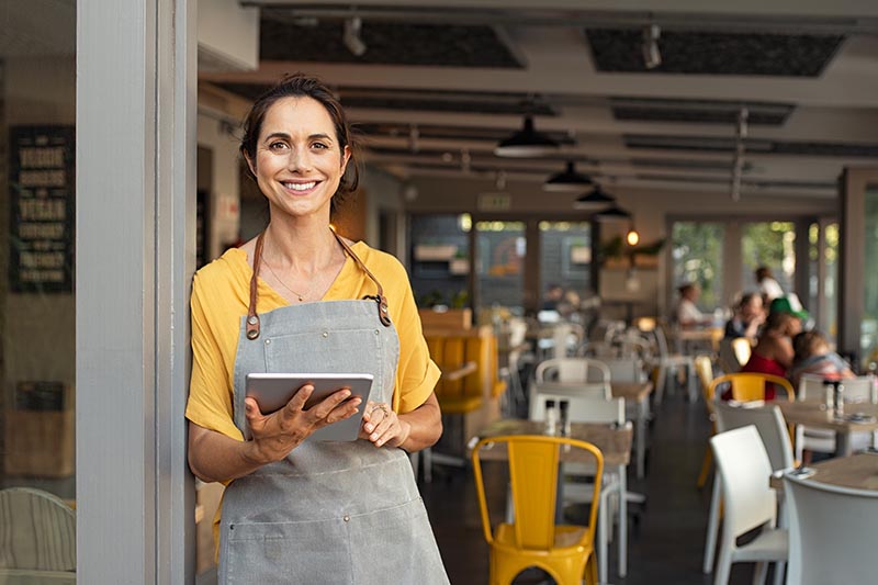 Restaurant owner standing in front seating area. 