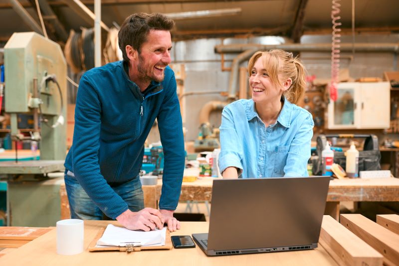 Small business owner at desk with notebook and laptop. 