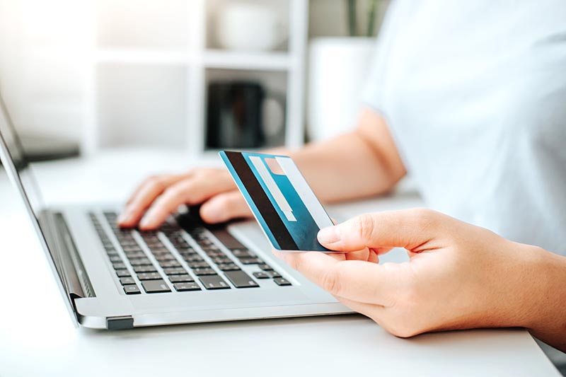 Customer using credit card to pay on laptop. 